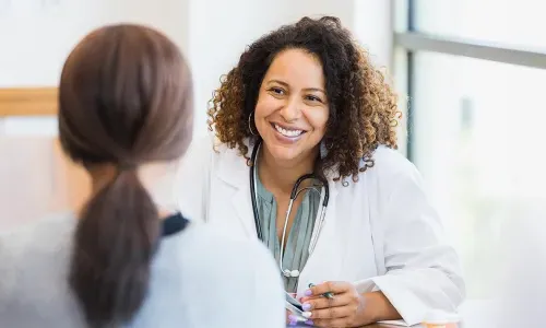 Women's health nurse practitioner smiling while speaking with female patient